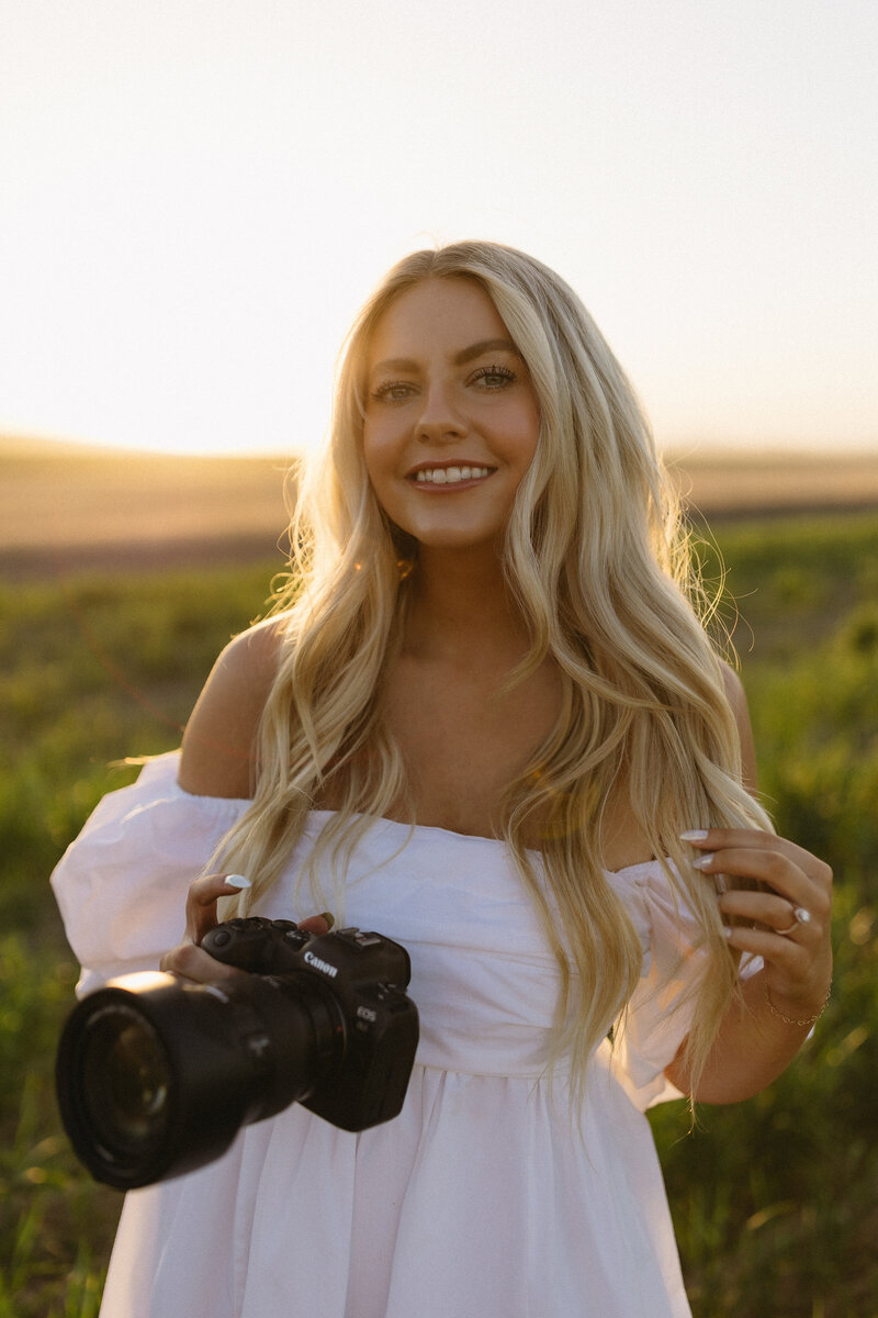 Wedding photographer in a white dress holding a camera.