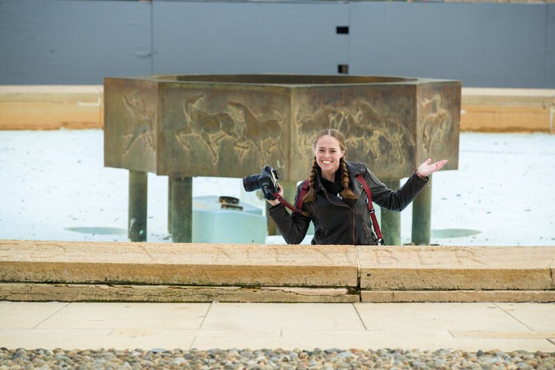 Jen Stitt standing in a fountain at the Philadelphia Museum of Art, preparing to capture a unique engagement session moment, blending creativity with the iconic setting of the museum.