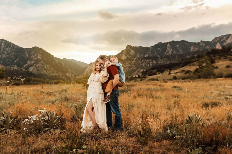 Mom, dad and son standing together in the Boulder mountains at sunset