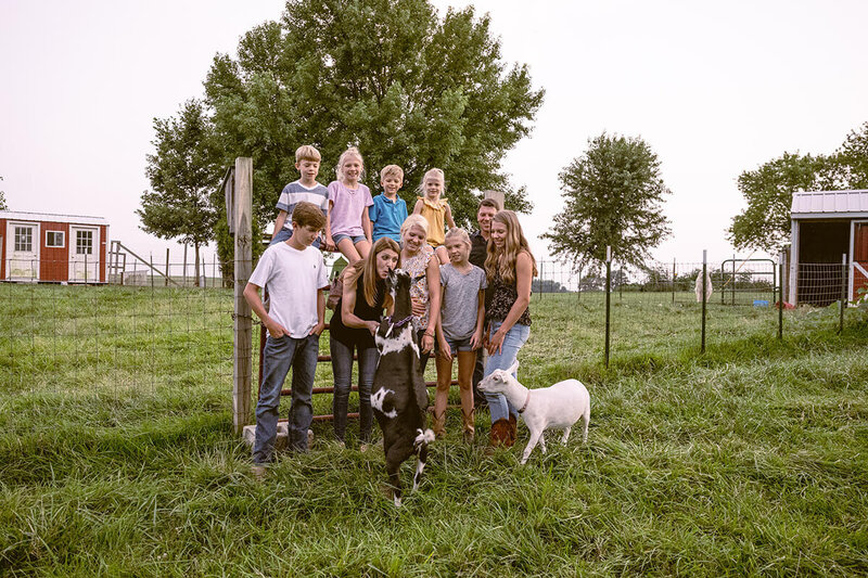 family at their homestead posing with their farm goats