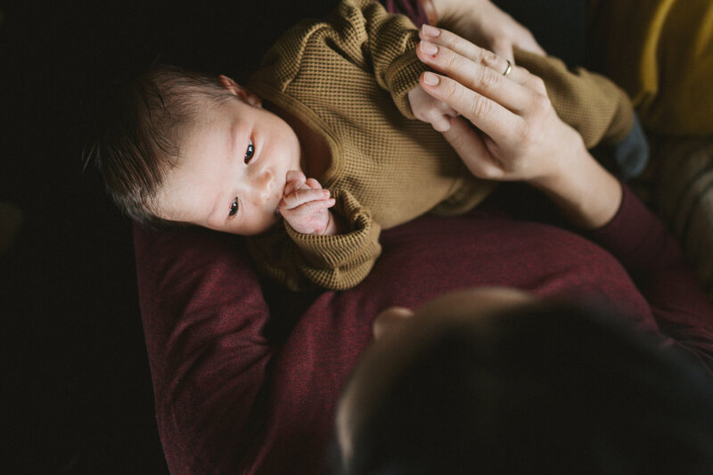 Baby liegt im Arm und schaut zu Mutter