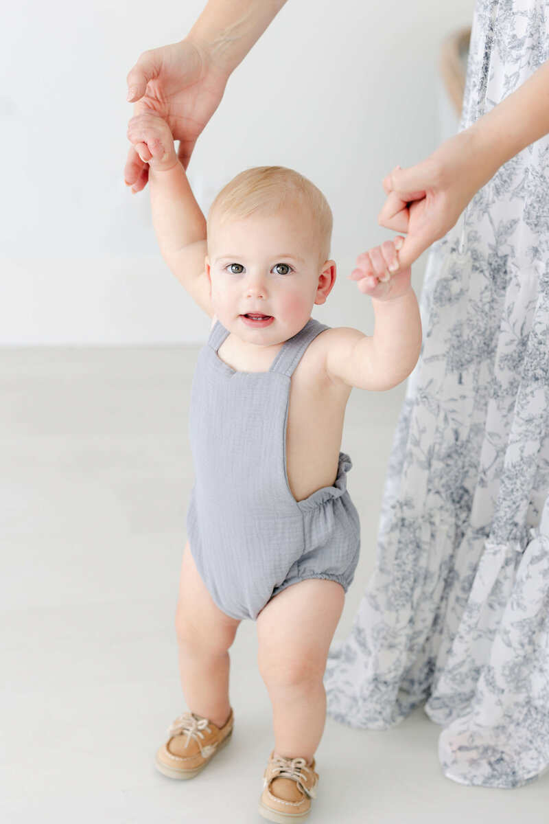 a mom helping her baby walk