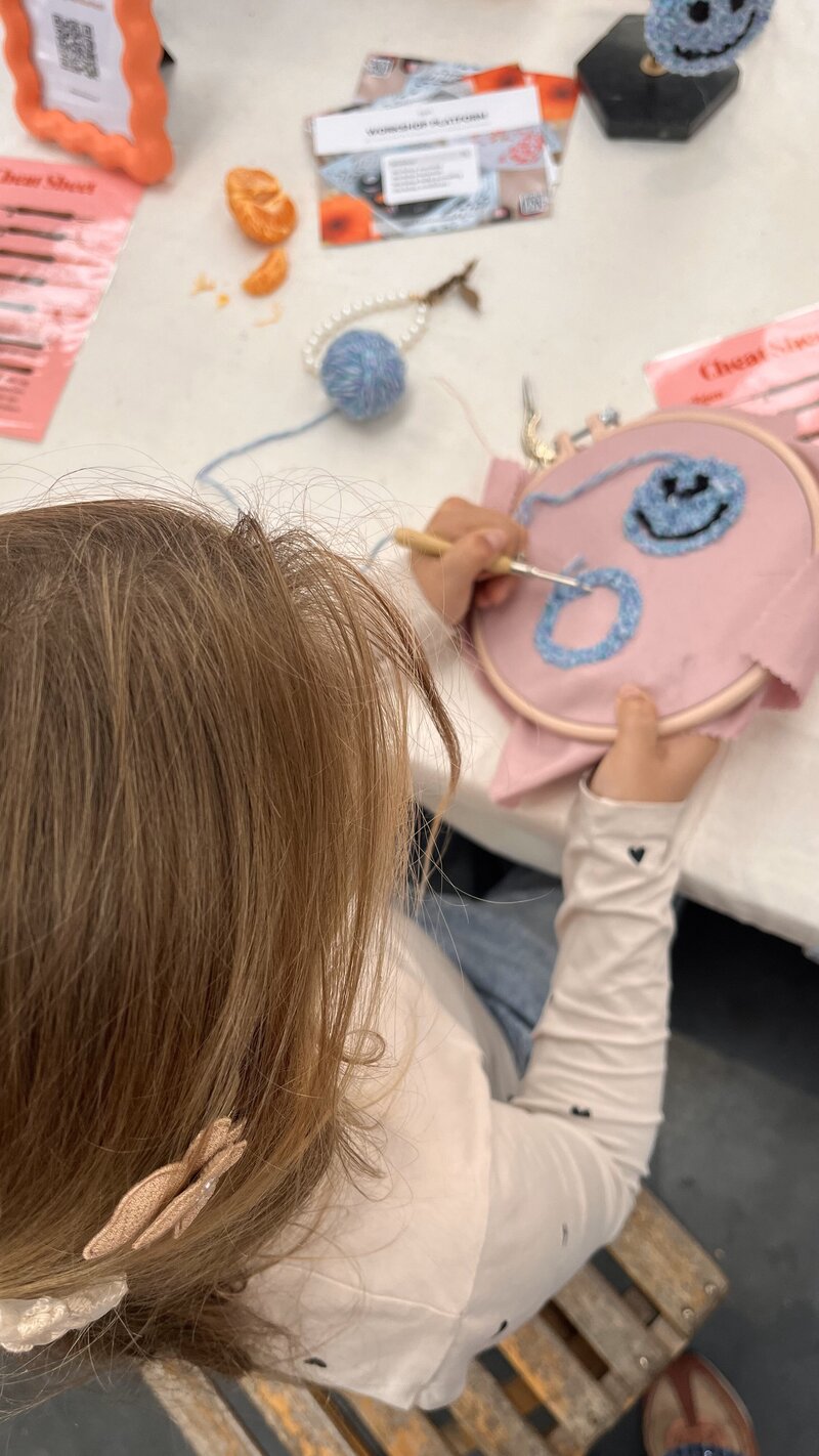 Kind aan het punch needlen tijdens een workshop