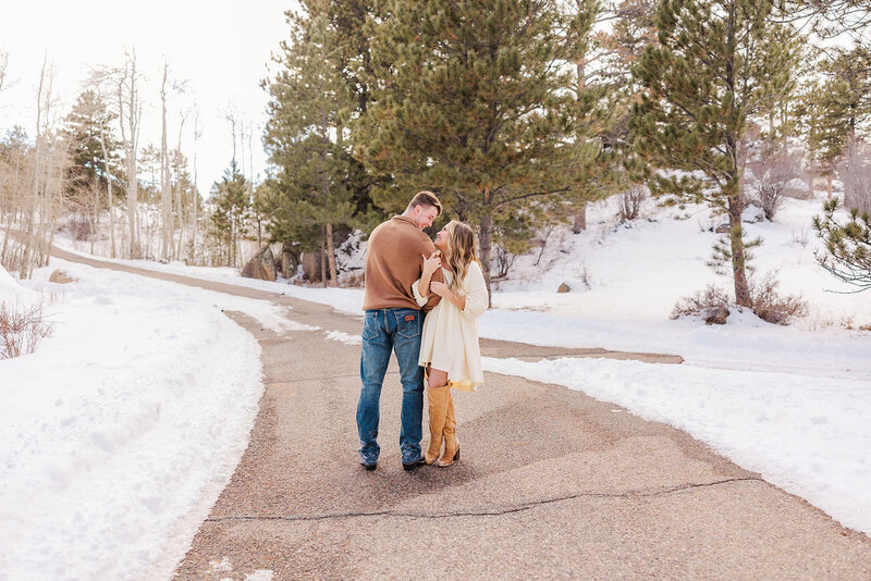 
Engaged couple sharing a tender moment during their engagement session at Hynds Lodge near Cheyenne, Wyoming, surrounded by a snowy landscape that enhances their love story.