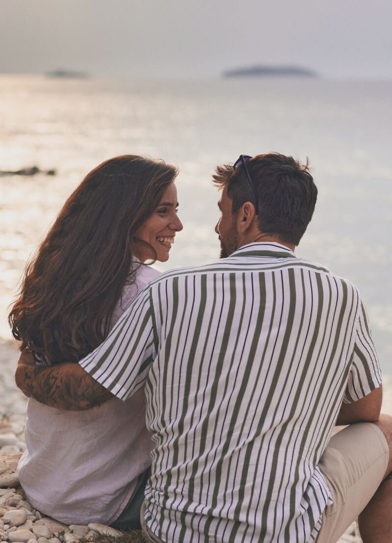 A man hugging his spouse on the beach  representing the joy a couple in the aftermath of infidelity can feel after utilizing the affair recovery online program: It's Okay to stay.
