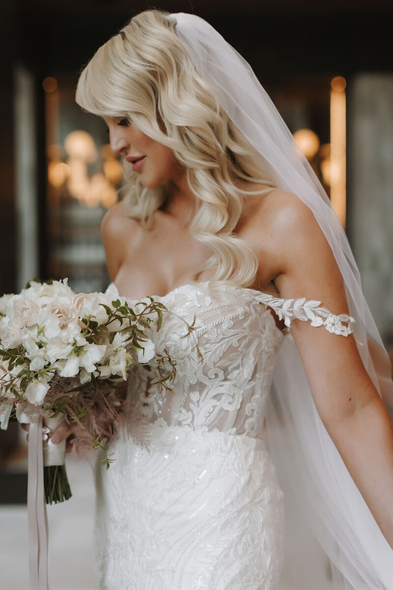 Bride posing in lace wedding gown with  baby pink wedding bouquet.