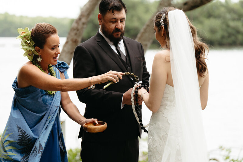 Hawaiian Officiant drips ocean water onto an eloping couples hands in a unity ceremony
