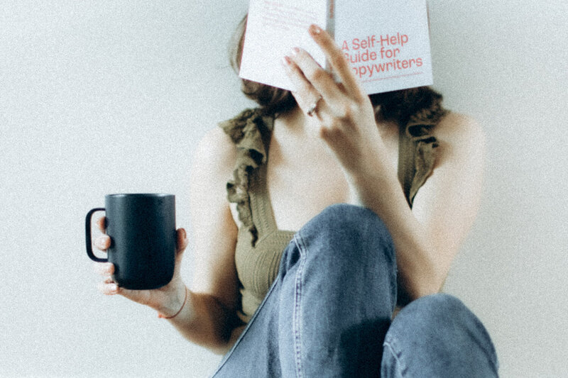 Andrea Shah's photo covering her face with an open book while holding a black mug