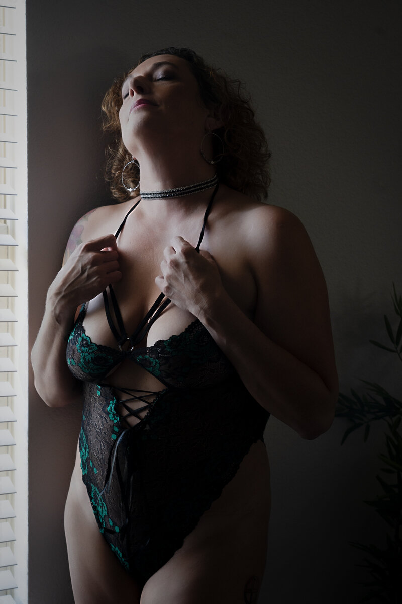 Boudoir photo of woman in green and back lacey bodysuit