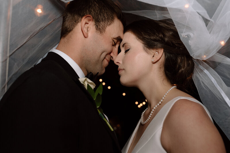 bride and groom kissing under the veil during their evening summer wedding