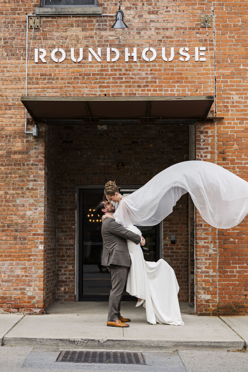 Couple kissing in the doorway of The Roundhouse in Beacon as the bride's veil blows in the wind