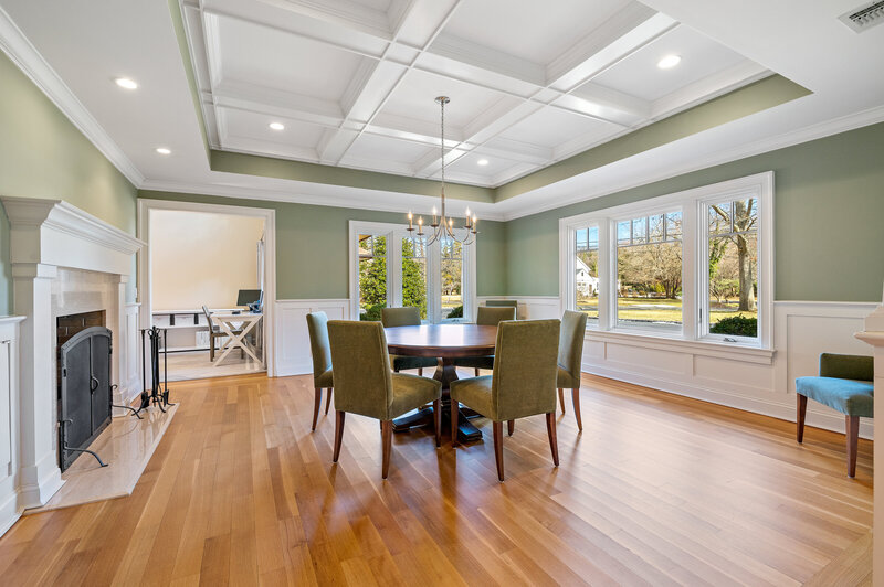 Renovated dining room in Cold Spring Harbor with coffered ceiling, wainscoting, hardwood floors, and large picture windows.