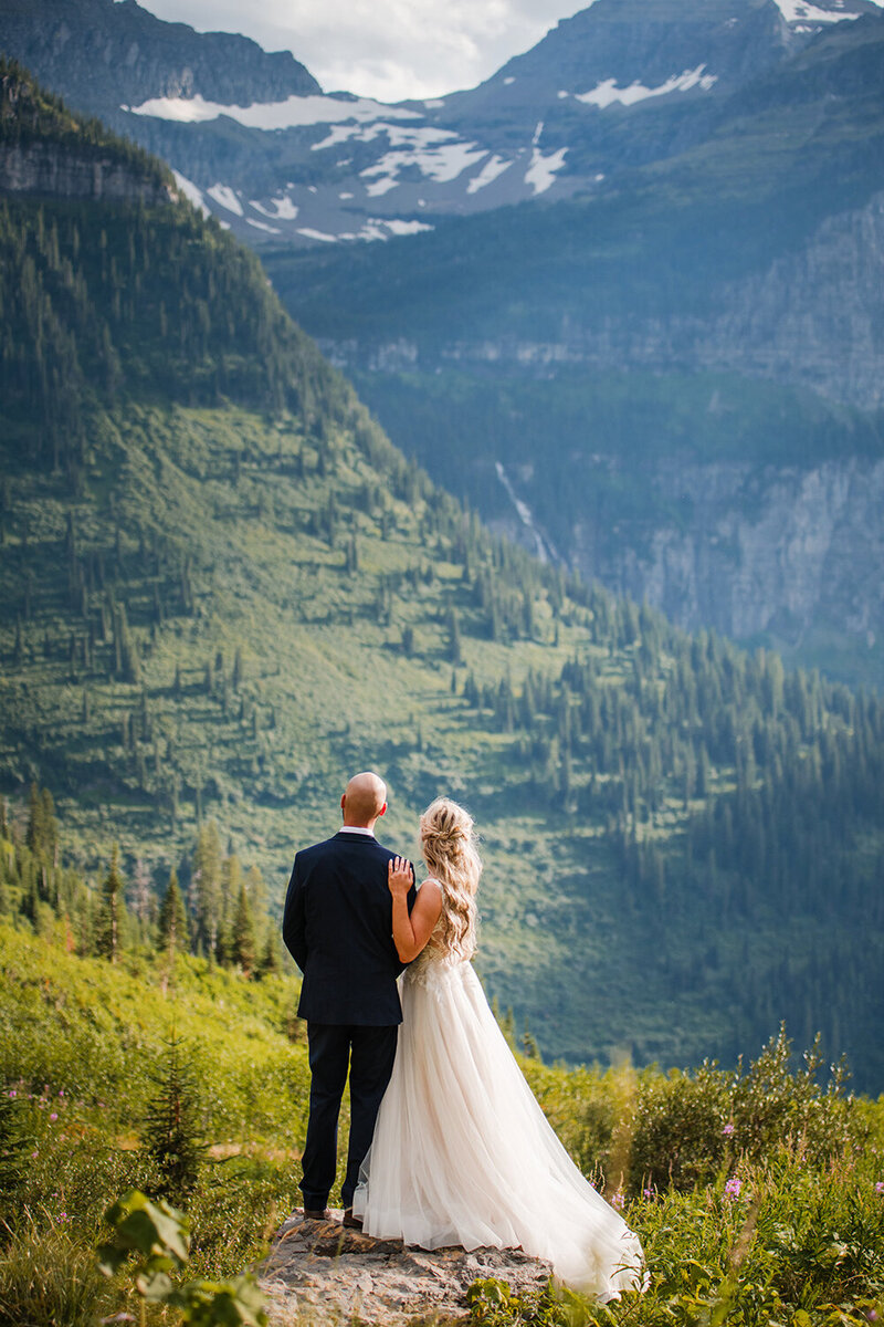 A bride and groom admire the stunning mountains of Glacier National Park in western Montana.