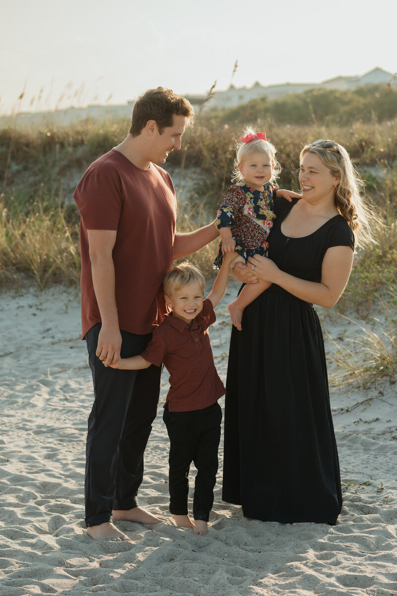 family of 4 on the beach smiling and connecting during family photo shoot near Orlando by Melissa Vinsik Photography