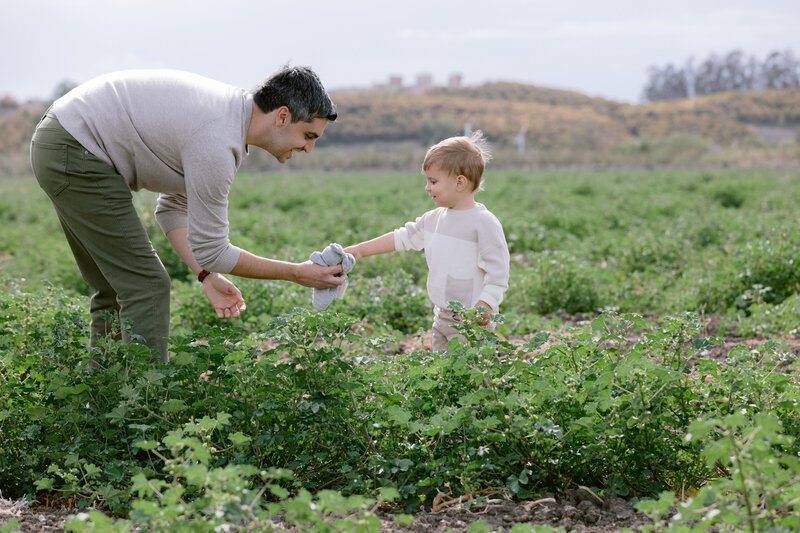 A dad reaching out to hand their child a stuffed animal