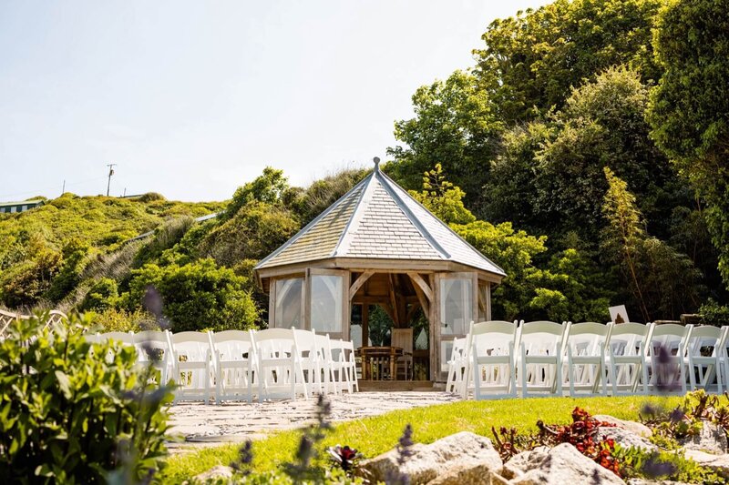 A beautiful summer house surounded by greenery and rows of white chairs