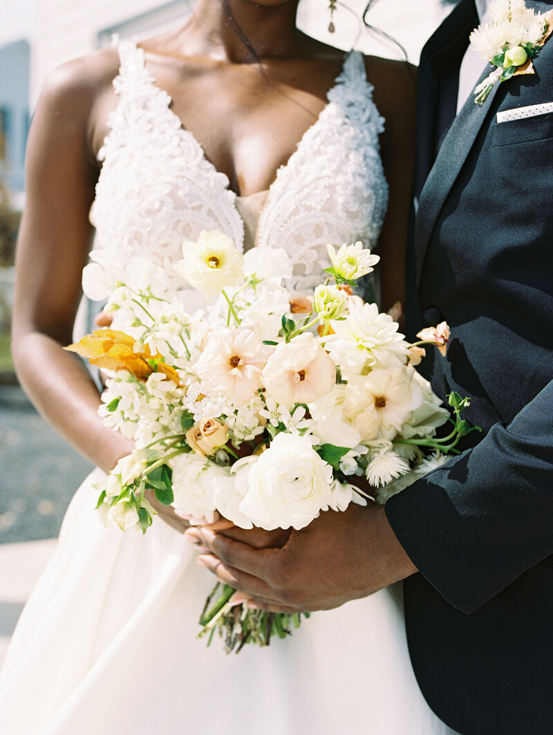 An African-American wedding couple holding a bouquet of white flowers together at Boxwood Manor