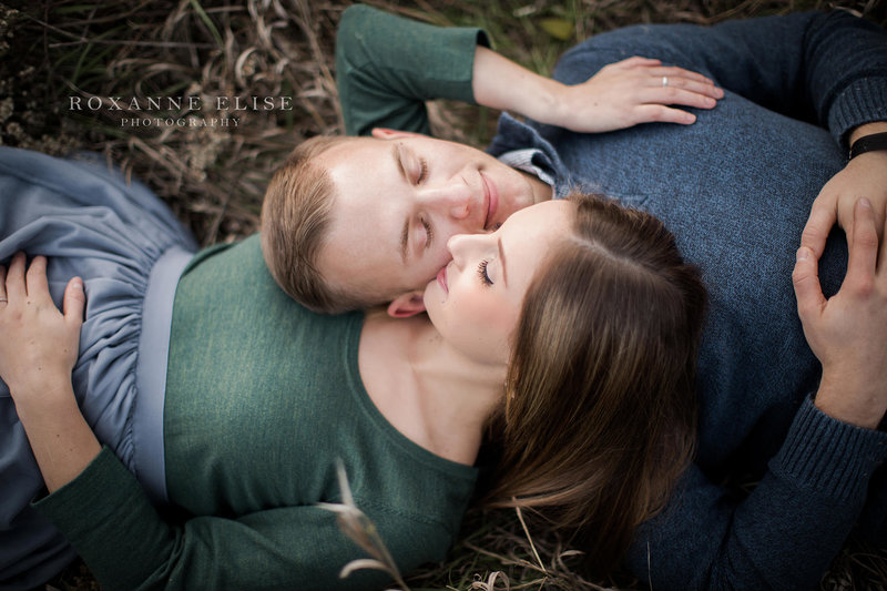 engaged couple lying in grass with eyes closed