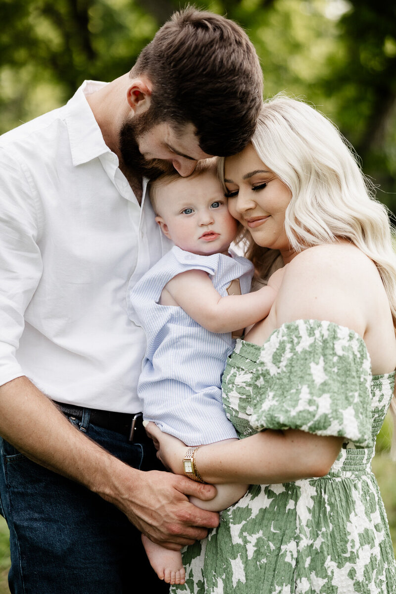 Summer family portrait session of parents with one year old boy in the center. 