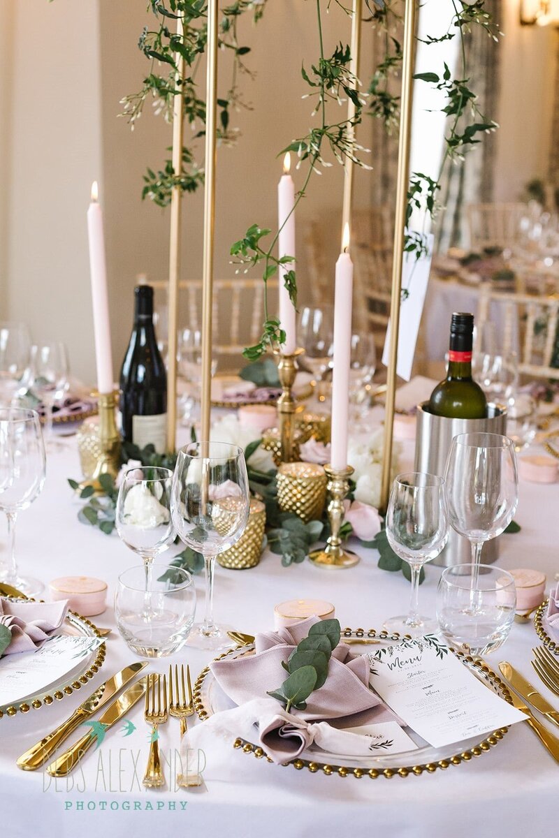 A wedding table with gold cutlery, gold tea lights and blush pink napkins