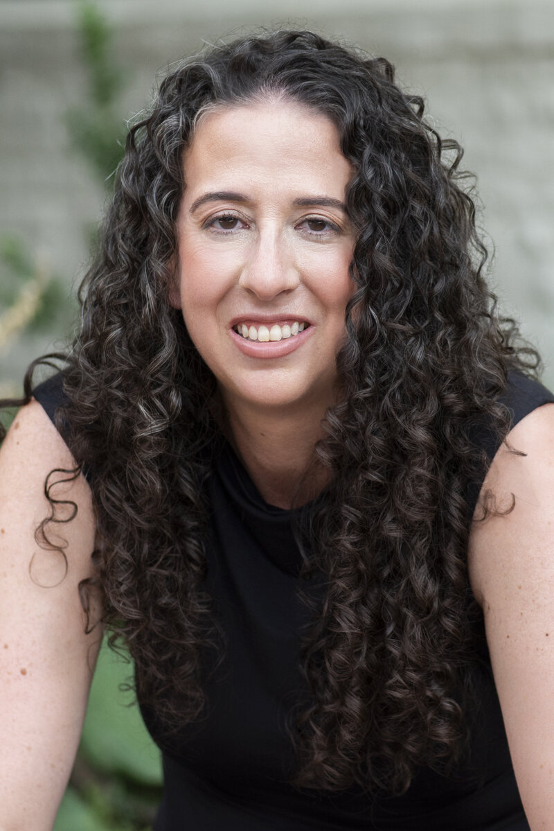 A person sitting down and leaning over while smiling 