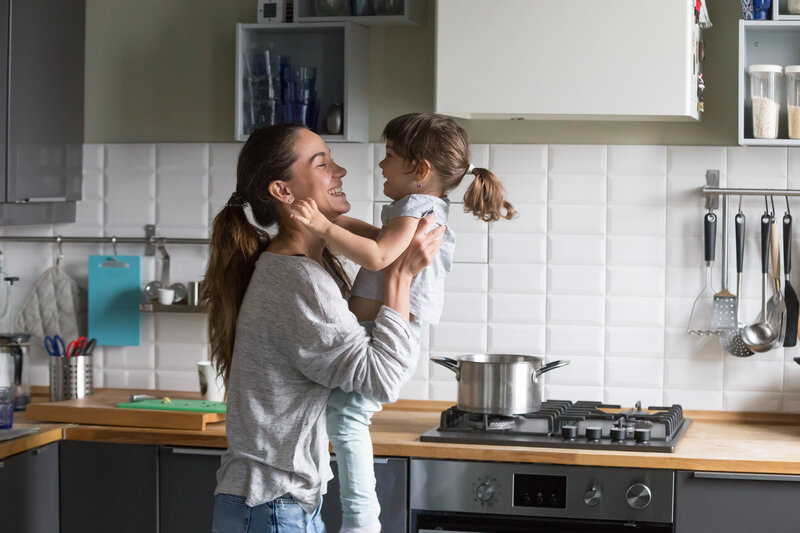 mom and daughter cooking in kitchen smiling with appliances