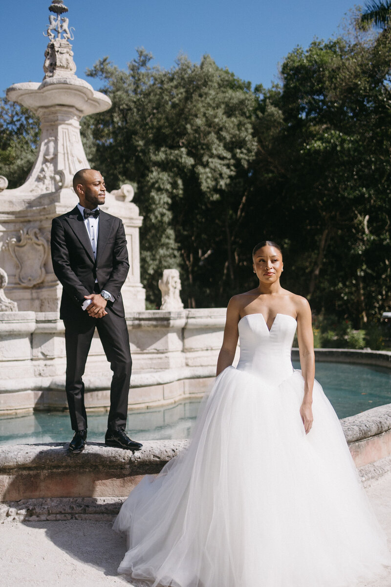 Newly wed Bride and Groom pose in front of a fountain at Vizcaya Musuem & Gardens, a destination wedding venue in Miami, FL, planned by Tyler Albritton, a wedding planner in Atlanta, GA