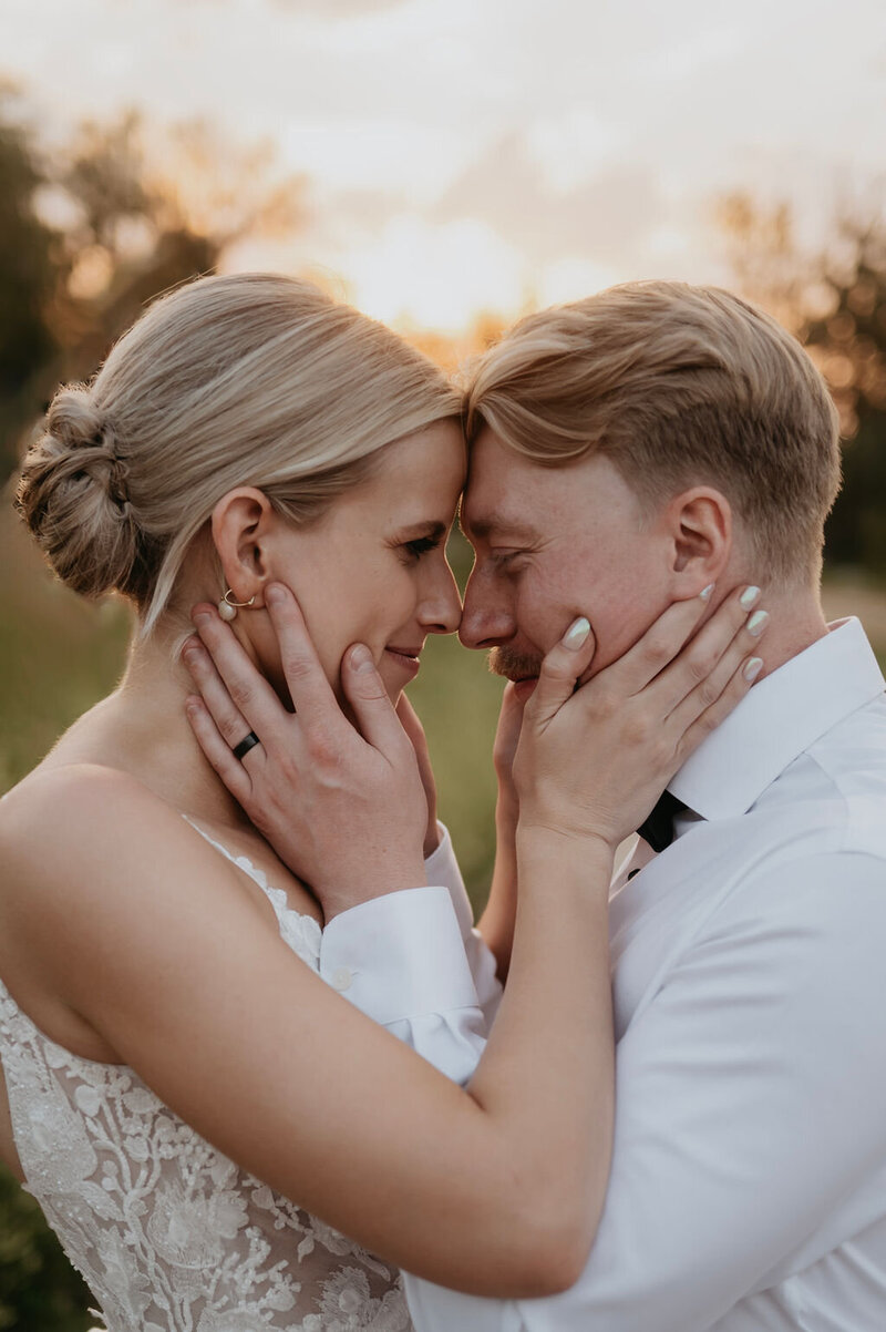 Close up of bride and groom looking at each other holding each other's faces.
