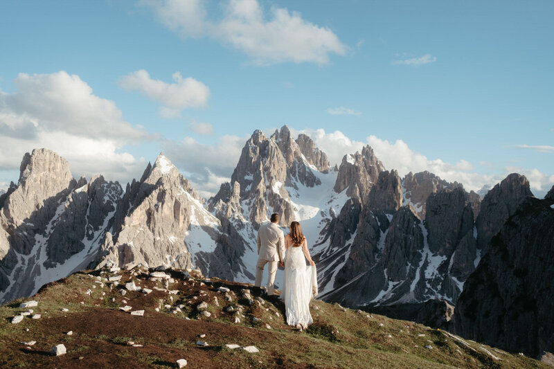 Eloping couple standing in front of a view of jagged snow-capped mountains for their Elopement Photo Ideas