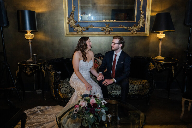 bride and groom on couch in lounge of The Ruins venue in Seattle for wedding day portraits