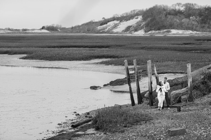 Black and white photo of an engaged couple sharing a timeless moment in the serene beauty of Cape Cod.