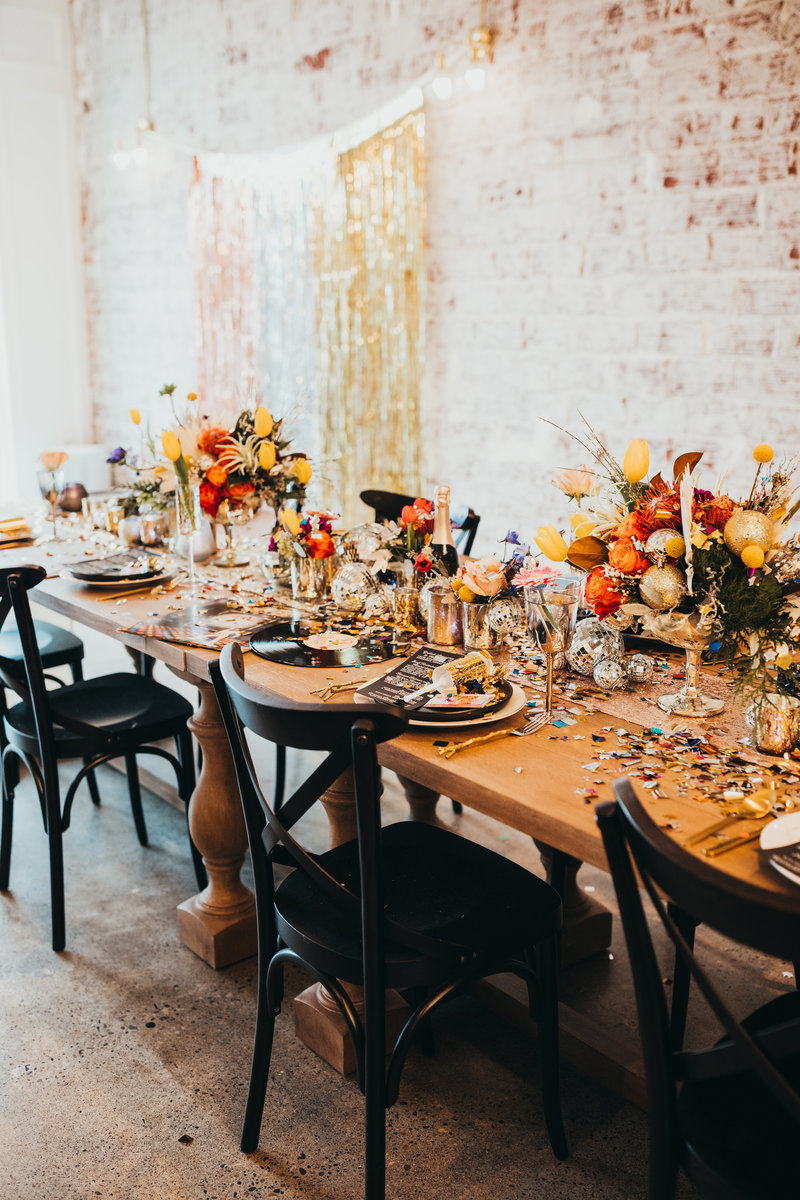 Details of a decorated table with flowers, candles, disco balls, and platters