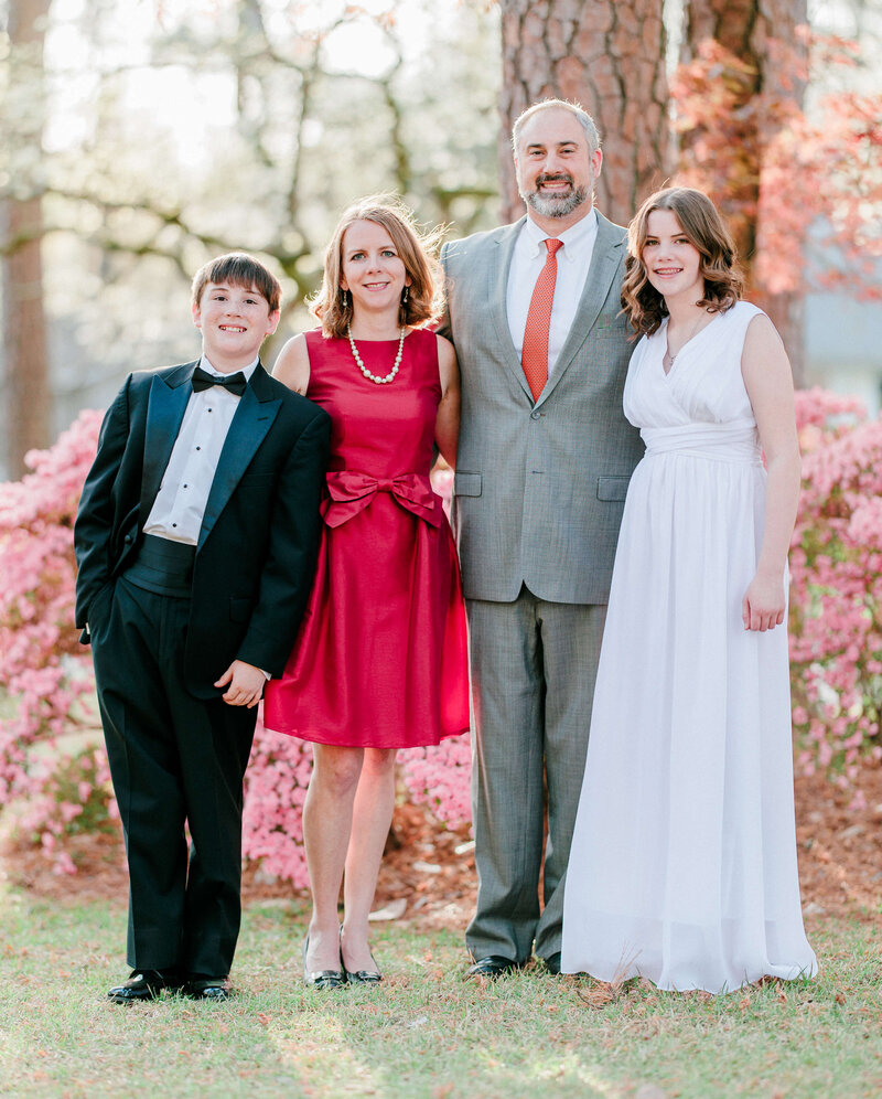 family of four posed for a family photo in a cherry blossom park