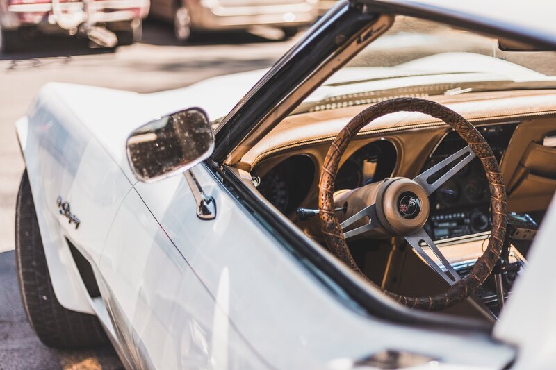 Drivers side view of a vintage white convertible with tan leather interior.