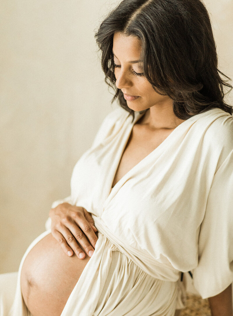 close up on bare pregnant belly with tan background