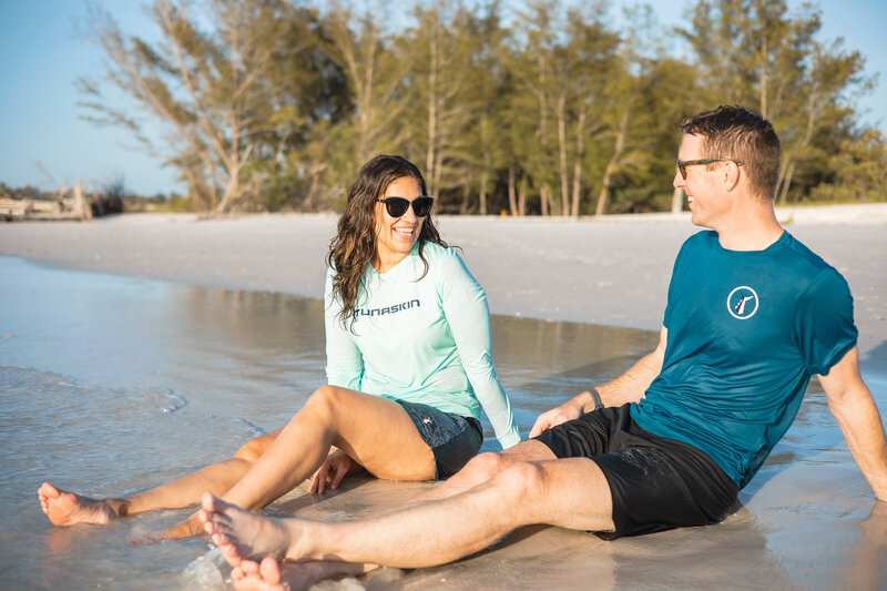 Couple sitting on beach wearing recycled plastic clothing for sun protection