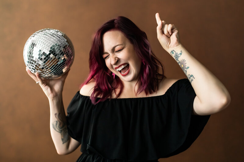 Saint Louis boudoir photographer, Boudie City, smiles while holding a disco ball