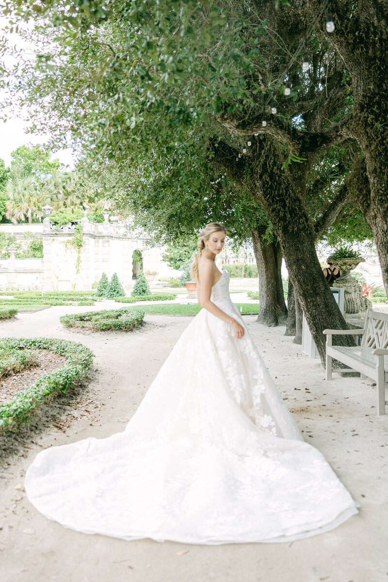 A stunning bride in an elegant ballgown poses gracefully in the lush gardens of Vizcaya Museum, Miami. This editorial wedding portrait captures timeless romance and luxury in one of Florida's most iconic wedding venues.