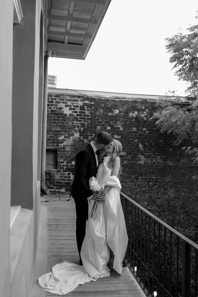 bride and groom kissing on the balcony at the pharmacy museum in new orleans