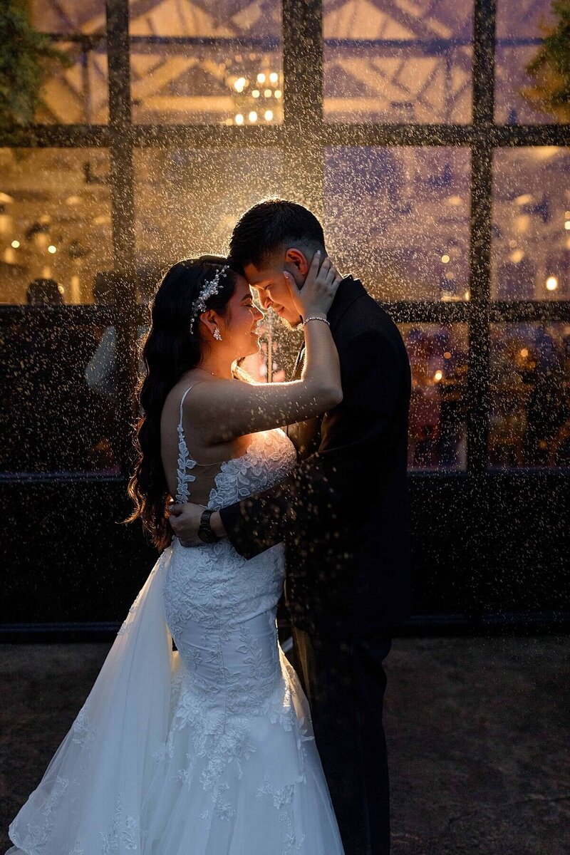Latino couple holding each other as it sprinkles rain at night