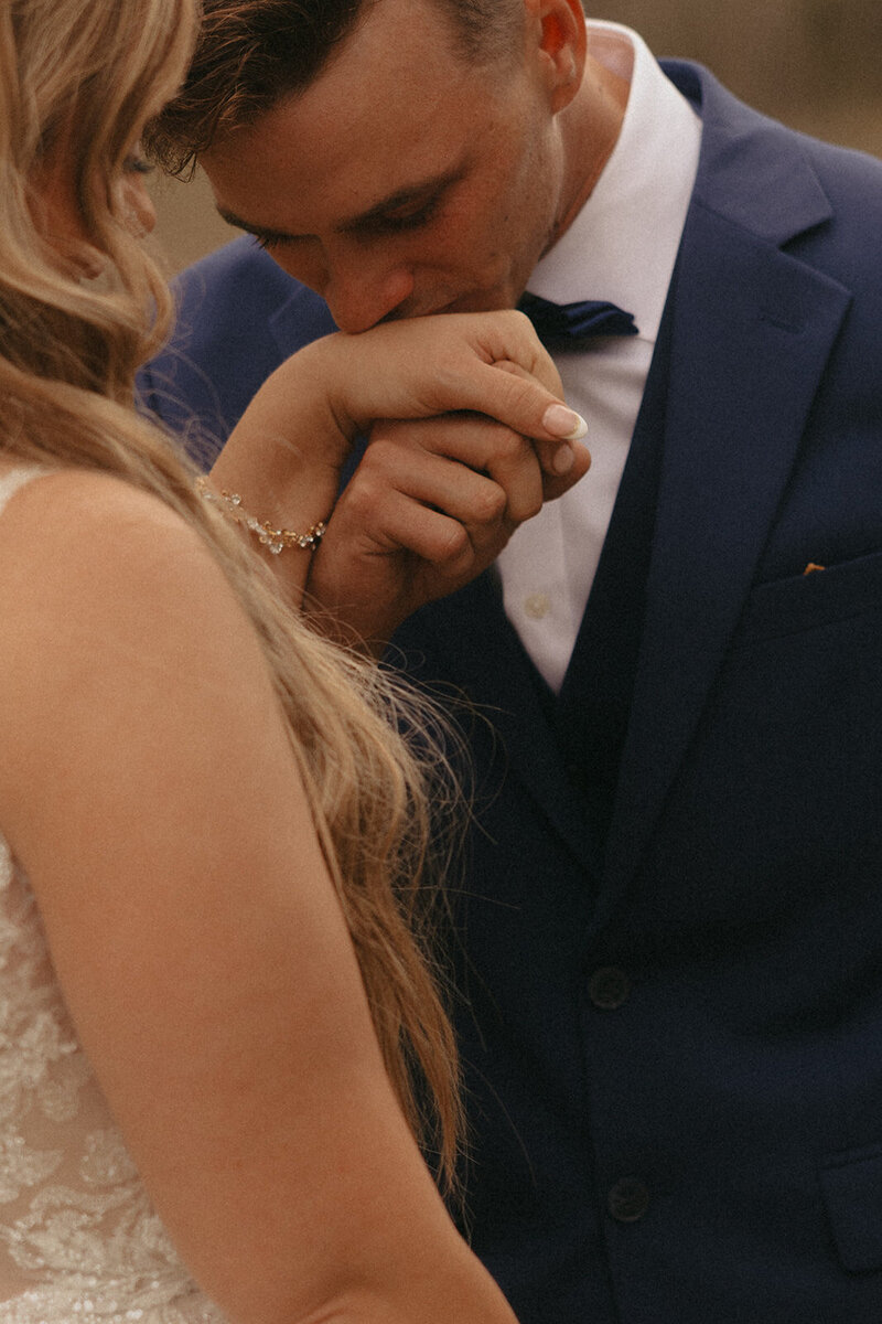 Groom gently kissing his bride's hand