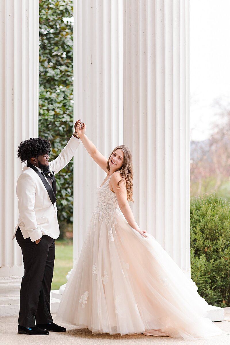 A portrait of a groom twirling his bride on the porch of their venue in Roanoke, Virginia  to get away from the rain.