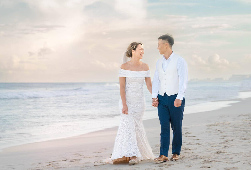 A bride and groom walking on the beach in Cancun at sunset