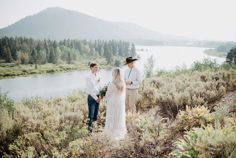 wyoming elopement with outdoor ceremony at oxbow bend with bride and groom standing with their officiant on a hill next to a river in the grand tetons
