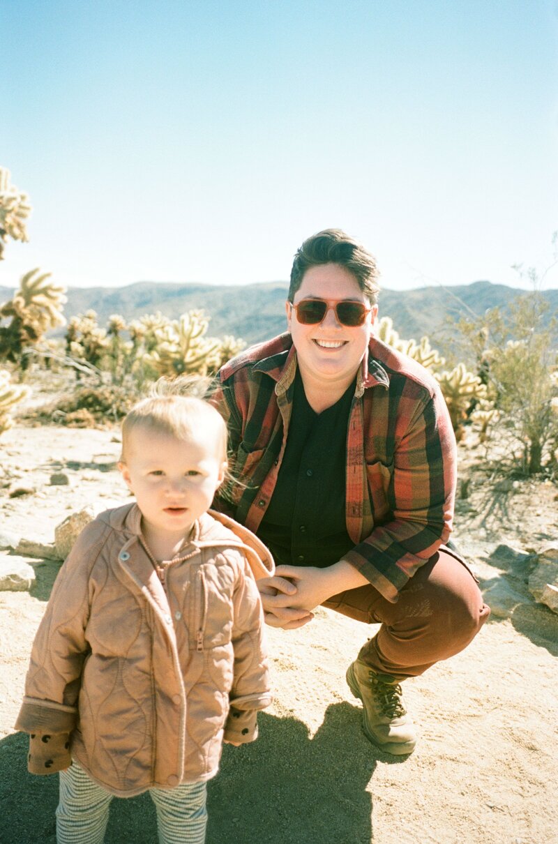Queer Wedding Photographer Theo Nash posing for a photo with their kid in Joshua Tree