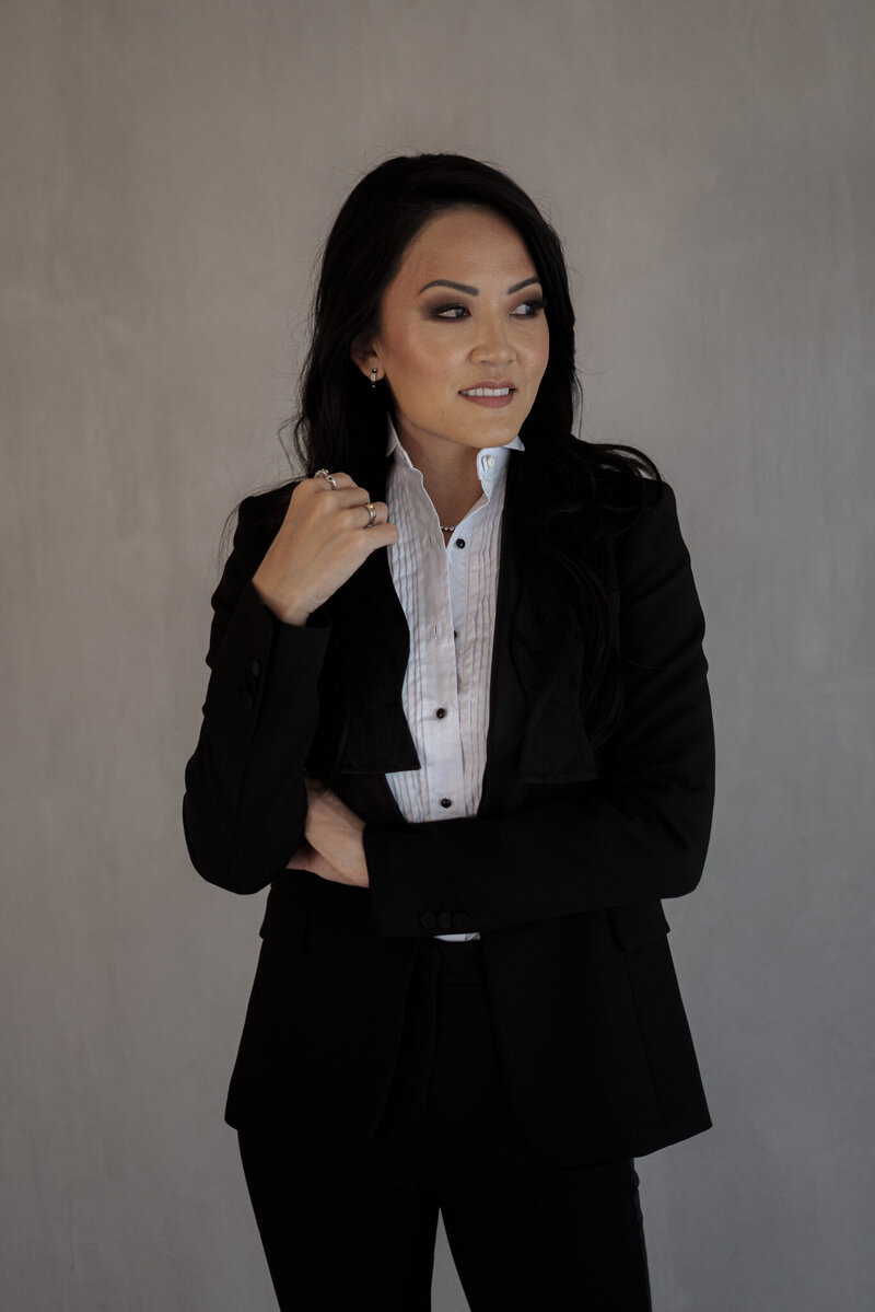 Professional portrait of Sandy, founder of Studio 23, wearing a tailored black suit and white shirt, embodying confidence and sophistication.