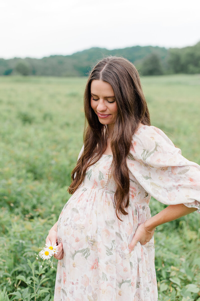 Pregnant mother holding florals and looking down at her belly during her Orlando maternity session