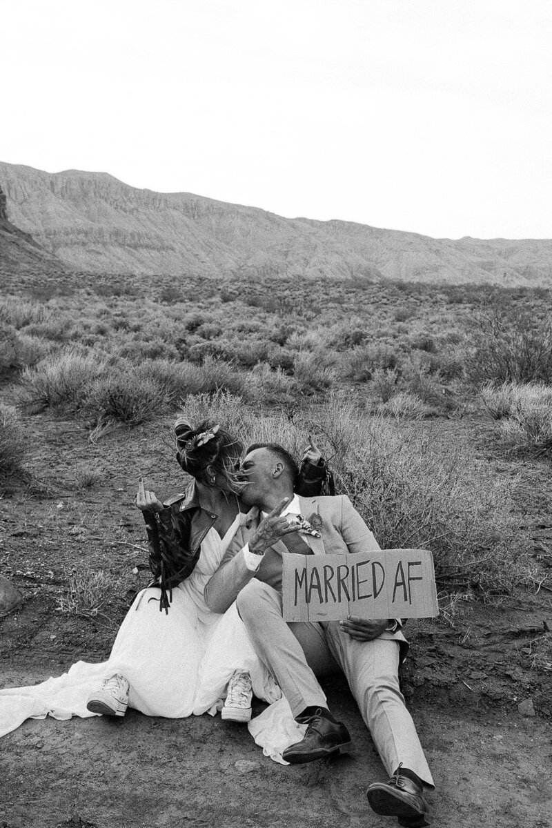 Couple holding a cardboard “Married AF” sign during their wedding celebration in the Pacific Northwest, photographed by Bare Bones Photo