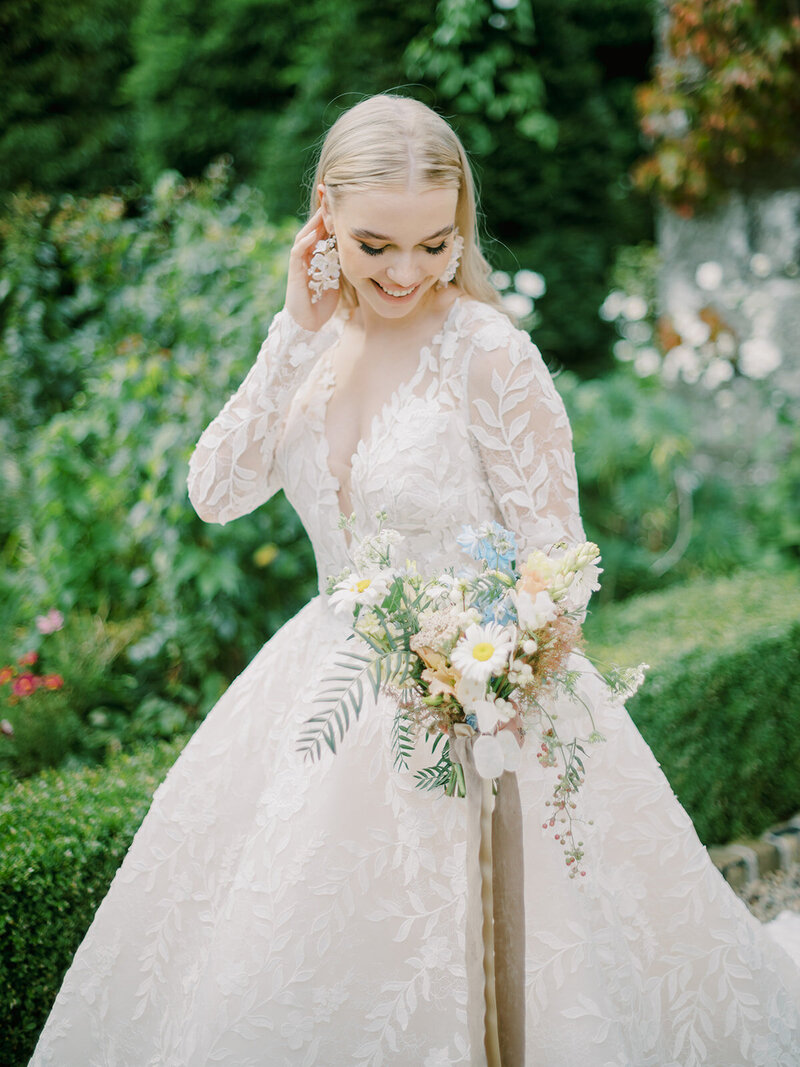 A-beautiful-bride-in-a-lace-wedding-dress-standing-in-a-garden