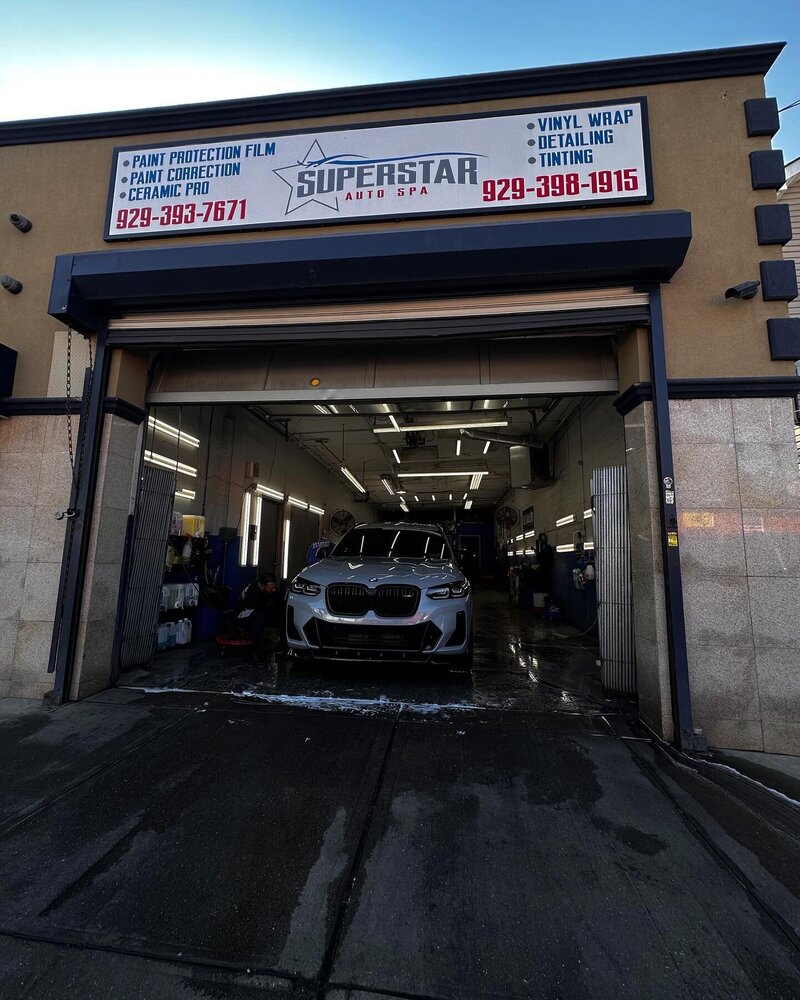Silver BMW X3 SUV entering the well-lit interior of Superstar Auto Spa in NYC, for professional car wash or auto detailing services. The image shows the entrance of the car wash bay, indicating the start of a thorough vehicle cleaning and care process at a trusted local auto spa. 